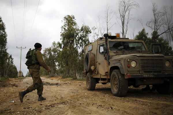 Soldado israelense caminha em direção a veículo militar durante patrulha na fronteira com Gaza, perto de Kibbutz Kissufim