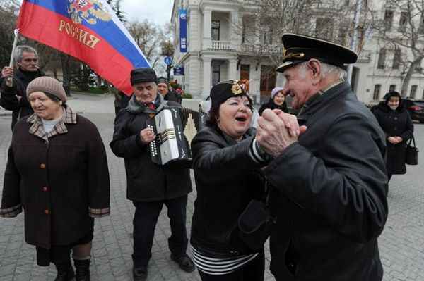 Um homem toca o acordeão enquanto pessoas dançam durante as celebrações em Sevastopol após a Criméia declarar independência