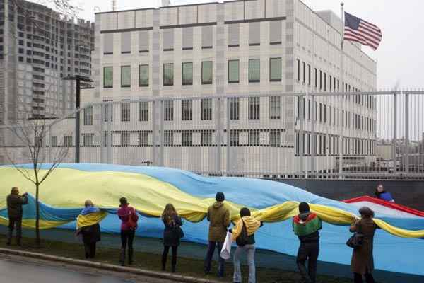 Pessoas estendem bandeiras da Ucrânia e da Crimeia em frente à embaixada dos Estados Unidos, em Kiev