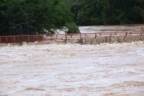 Água do rio Itapecerica inunda passarela que liga o bairro Esplanada ao bairro Porto Velho, após cheia do rio devido à chuva