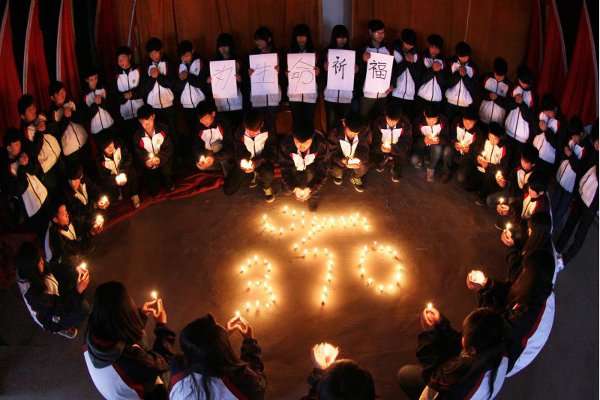 Estudantes seguram velas durante vigília para passageiros do Boeing 777-200 da Malaysia Airlines, na cidade chinesa de Lianyungang