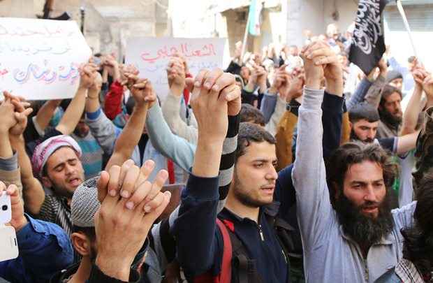 Manifestantes anti-governo dão as mãos enquanto marcham durante o funeral de um homem, morto pelas forças leais ao presidente da Síria, Bashar al-Assad