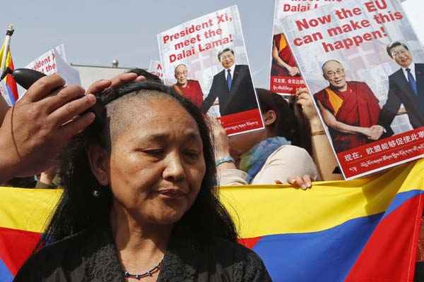 A ativista tibetana raspa cabelo durante uma manifestação contra a visita do presidente chinês, Xi Jinping, em Bruxelas