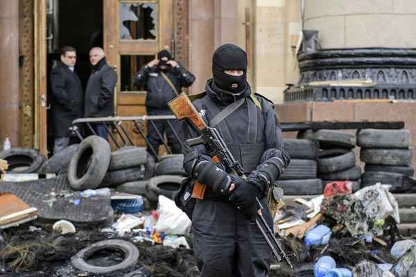 Homem armado mascarado, que representa as forças especiais da Ucrânia, fica de guarda do diante do prédio da administração regional em Kharkiv