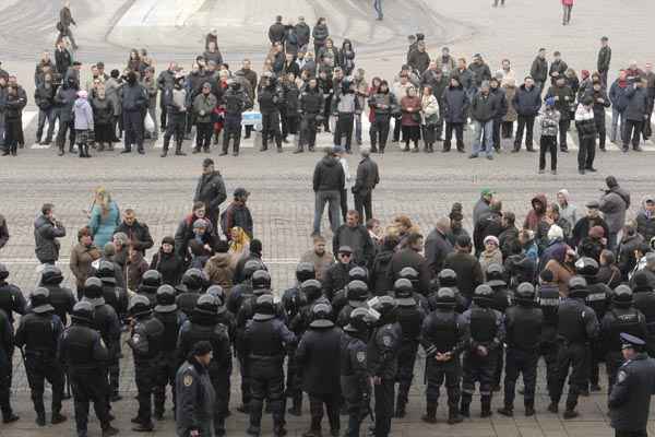 Pessoas se reúnem diante do Ministério do Interior enquanto forças de segurança fazem guarda no local, em Kharkiv