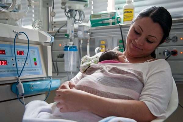 Colombiana Eileen Johanna Jaimes segura seu bebê prematuro diretamente contra seu corpo, na unidade neonatal de cuidados intensivos do hospital de San Ignacio, em Bogotá