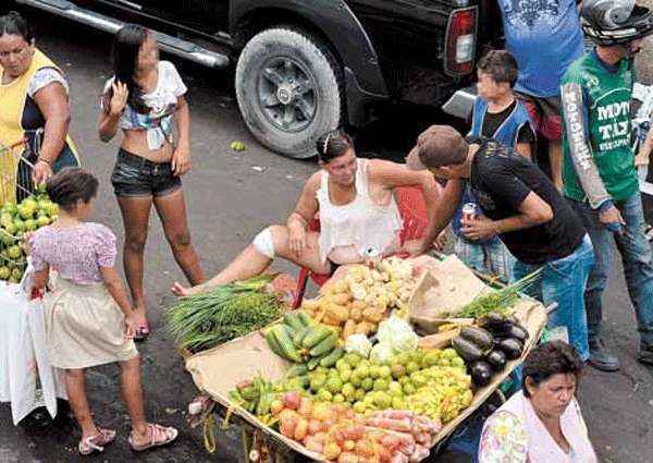 Adolescentes com o corpo à mostra abordam clientes para vender as rifas em feira ao ar livre, perto do Porto de Manaus