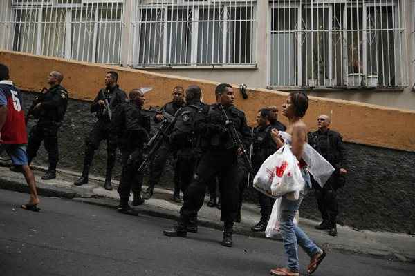 Moradora anda na frente de policiais na favela Pavão-Pavãozinho, no bairro de Copacabana