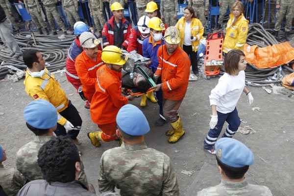 Equipes de resgate carregam mineiro que se macgucou depois da explosão de uma mina, em Soma