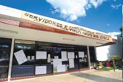 Cartazes na entrada da biblioteca demonstram a indignação da comunidade com a situação do espaço