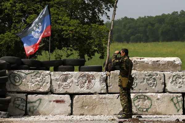 Ativista pró-Rússia olha através de binóculos em local ocupado na periferia da cidade ucraniana de Slaviansk