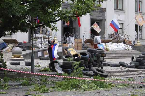 Homem segura bandeira russa em frente ao prédio da administração regional de Luhansk, no Leste da Ucrânia