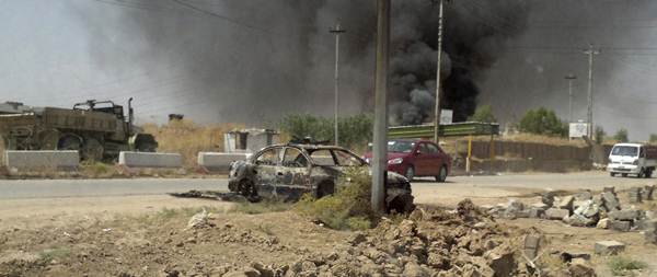 Um veículo queimado das forças de segurança do Iraque é visto em uma estrada um dia depois de insurgentes sunitas radicais tomaram o controle da cidade de Mosul