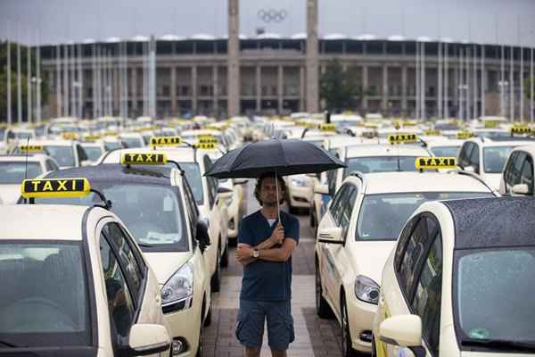 Um homem caminha entre táxis em frente ao estádio Olímpico de Berlim, na Alemanha