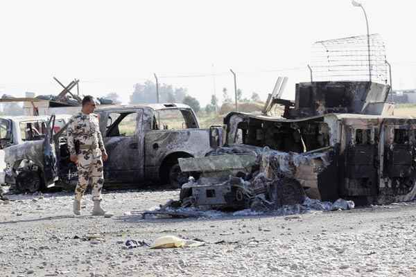 Soldado olha para destroços de veículo pertencente às forças de segurança iraquianas nos arredores de Kirkuk