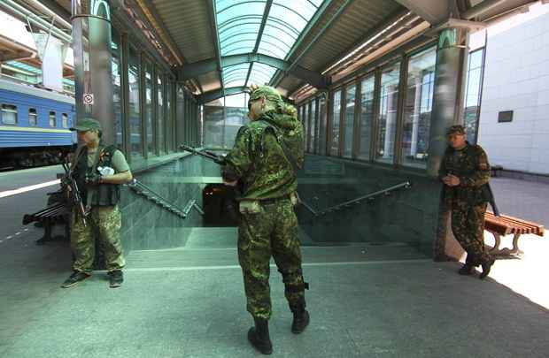 Armadas separatistas pró-russos ficam de guarda em uma estação ferroviária