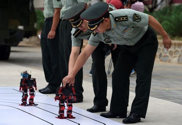 Soldados do Exército de Libertação ajustam robôs dançantes