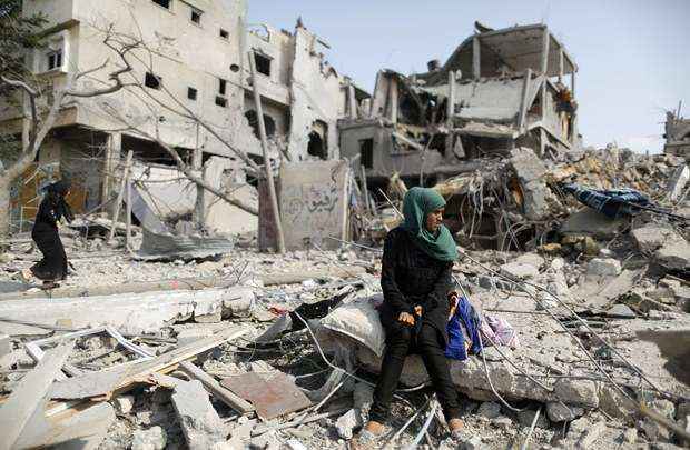 Palestina se senta sobre as ruínas de casa destruída por ataques e bombardeios aéreos israelenses