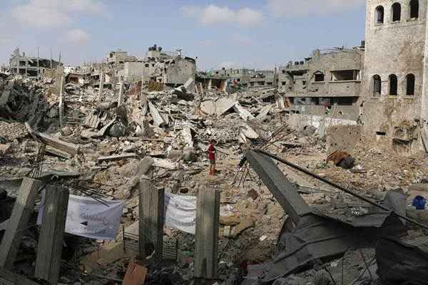 Menino entre as ruínas de edifícios destruídas por ataques aéreos israelenses no bairro de Shejaia, na Cidade de Gaza