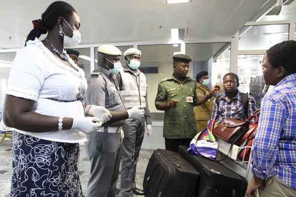 Funcionários de máscara recebem passageiros em aeroporto da Nigéria