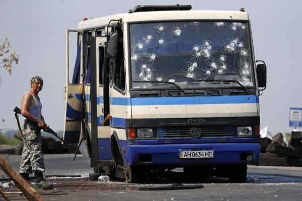 Separatista pró-russo armado anda perto de ônibus que foi alvejado por tiros, na periferia de Donetsk