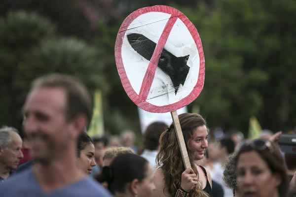 Jovem segura placa com mensagem contra mísseis em encontro que pede a rápida solução do conflito entre Israel e Hamas, em Tel Aviv