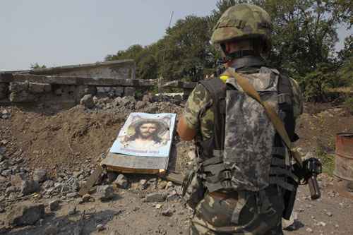 Soldado ucraniano fotografa imagem religiosa no chão, perto de escombros: Reduto separatista tinha um milhão de habitantes antes do conflito