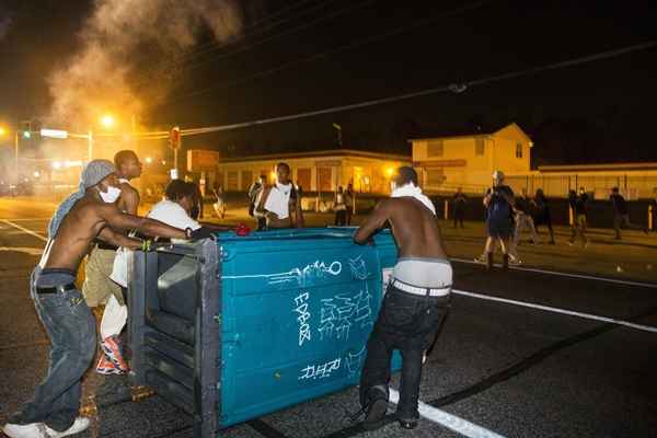 Manifestantes arrastam um banheiro portátil para a estrada durante protestos em reação ao assassinato de Michael Brown,perto de Ferguson, em Missouri, nesta segunda-feira (18/8)