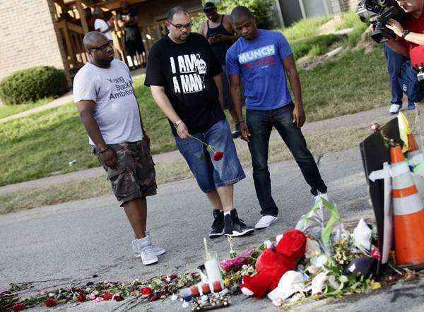 Homens coloca uma rosa em um memorial improvisado para Michael Brown, em Ferguson, Missouri, nesse domingo (24/8)