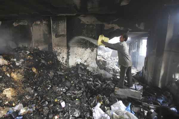 Homem joga água para apagar incêndio em ruínas de edifício que teria sido atingido por ataque aéreo israelense, em Khan Younis, no sul da Faixa de Gaza