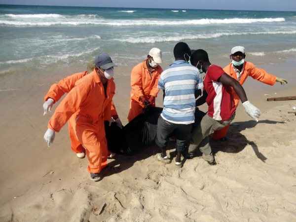 Equipe de resgate embala corpos de naufrágio em sacos na beira da praia, na Líbia