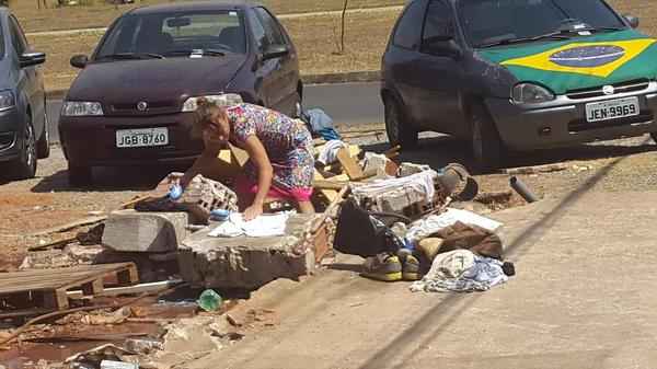 Moradora de rua aproveita registro para lavar roupa