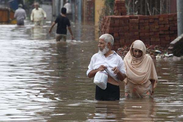 Casal caminha em estrada inundada, após chuvas torrenciais em Lahore