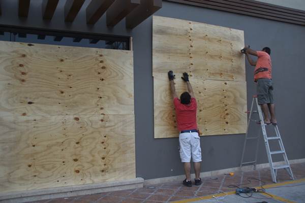 Trabalhadores de loja colocam tábuas em paredes para evitar danos no prédio durante a passagem do furação, em La Paz, na Baja Califórnia