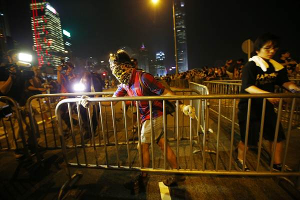 Manifestante carrega uma cerca de metal e tenta bloquear uma avenida em Hong Kong