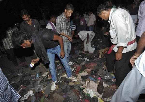 Pessoas buscam pertences entre os sapatos deixados para trás durante um tumulto na cidade indiana oriental de Patna