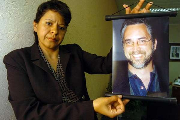 Viúva do educador assassinado, Rita de Cassia Pereira mostra foto da vítima, Carlos Mota