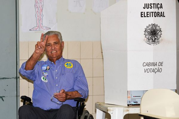 Candidato acena, com broches de apoio aos candidatos à presidência e ao governo