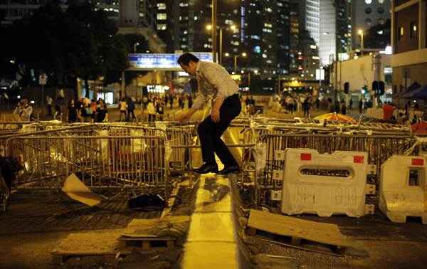 Um homem caminha por uma barricada em uma área bloqueada por manifestantes pró-democracia, perto da sede do governo em Hong Kong