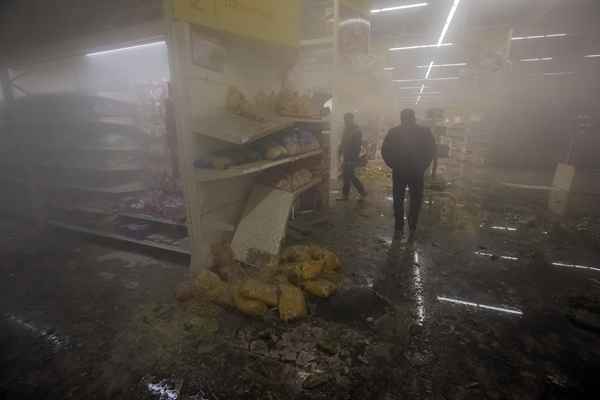 Pessoas caminham dentro do centro de compras Amstor depois de ele ter sido bombardeado