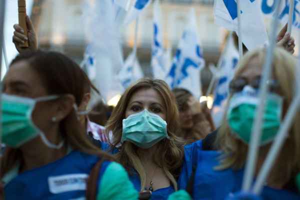 Manifestantes usam máscaras cirúrgicas para protestar contra a postura do governo sobre o ebola, em Madrid