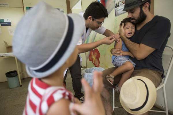 Estevão, de 2 anos, é observado pelo irmão Emanuel Castelo Branco,de  4 anos, enquanto é vacinado em um posto de saúde do Distrito Federal