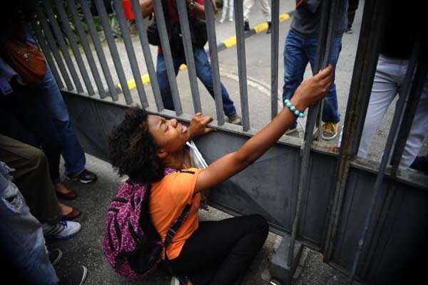 Desesperada, estudante se atira ao chão ao encontrar o portão do local de sua prova fechado. 