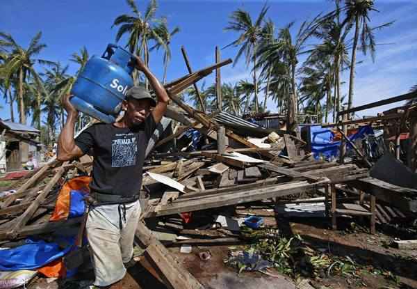 Homem anda sob os escombros da casa destruída pelo tufão Hagupit