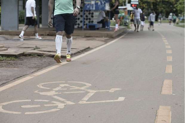 Homem caminha na pista destinada ao trânsito de bicicletas: risco constante devido à falta de espaço