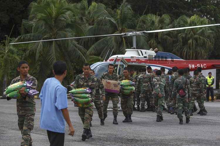 Soldados malaios carregam suprimentos de emergência em Kuala Krai