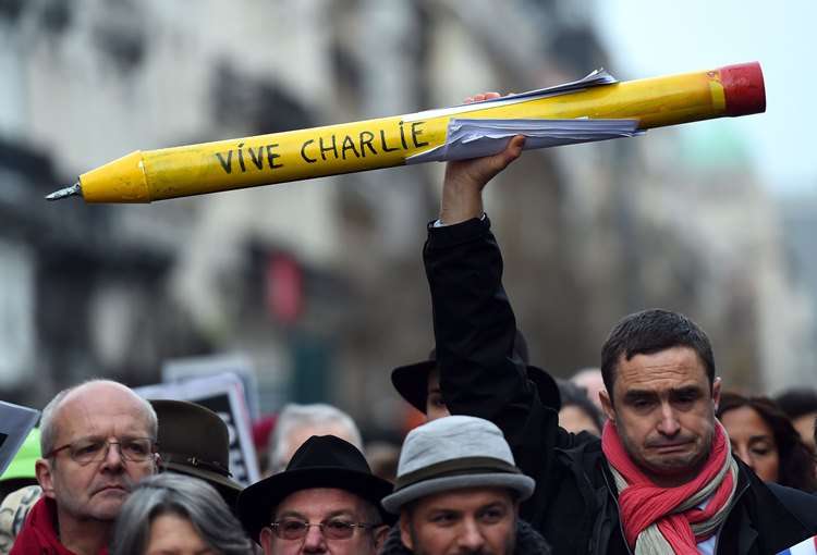 Homem segura um lápis com a frase 'Vive Charlie' em Bruxelas