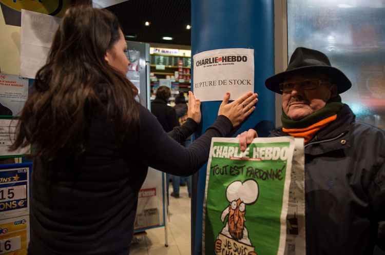 Outro leitor segura a revista, enquanto mulher fixa cartaz na entrada da banca afirmando que os exemplares foram esgotados