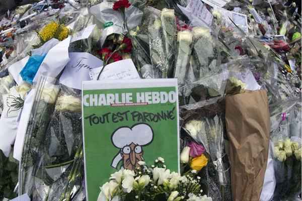 Uma cópia da última edição da Charlie Hebdo é colocada entre as homenagens em frente à sede da revista, em Paris