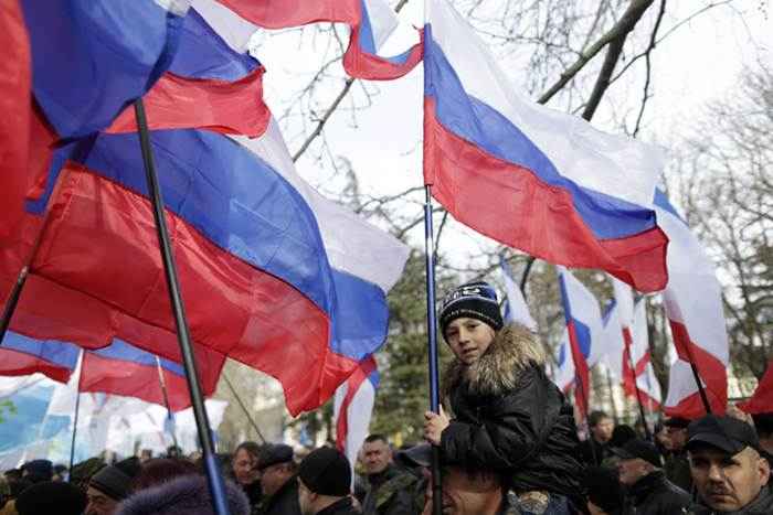 Menino segura  bandeira russa durante ato que marcou o aniversário de um ano da votação para a Crimea  deixar a Ucrânia e se anexar ao Estado russo